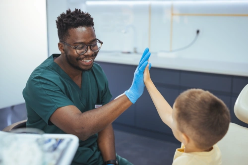 Dental assistant high fiving pediatrics patient after successful